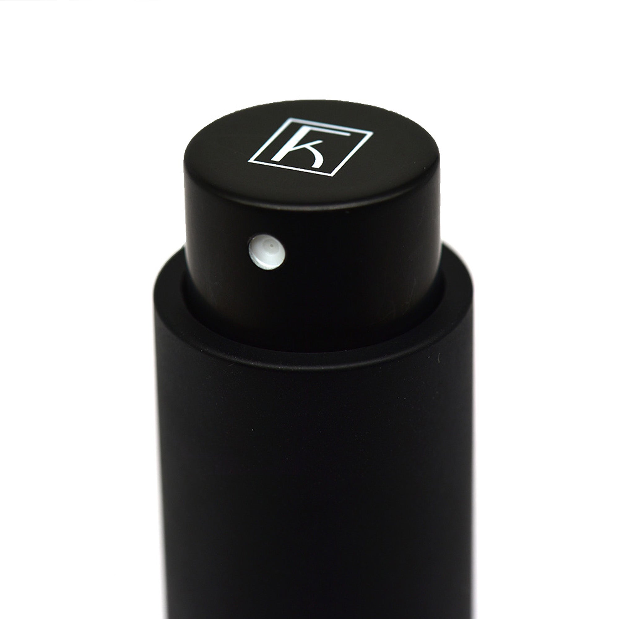 Ein schwarzer Zerstäuber-Flakon, vermutlich für Parfüm, mit weißem Sprühkopf und einem weißen K-Logo auf der Oberseite.