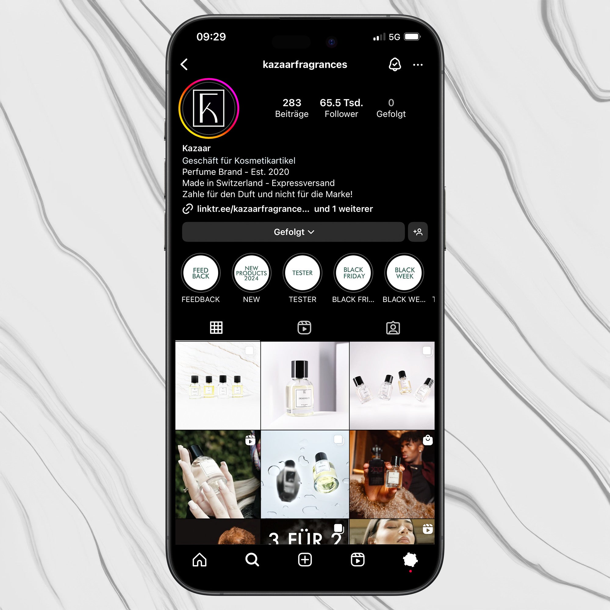 Ein schwarzes Smartphone liegt auf einer Marmor-Oberfläche und zeigt ein Instagram-Profil von "Kazaarfragrances" mit Parfümflaschen, Highlights und Beiträgen.